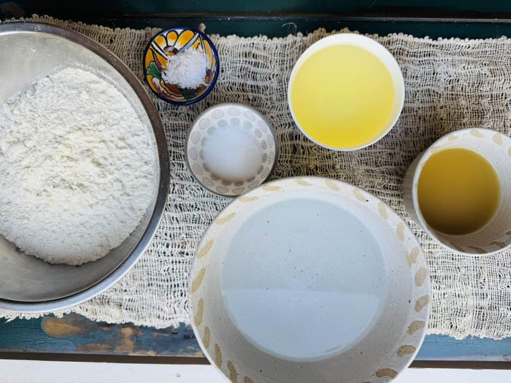 Ingredients for vegan tamales in bowls Maseca flour, vegetable broth, oil, salt, baking powder, water