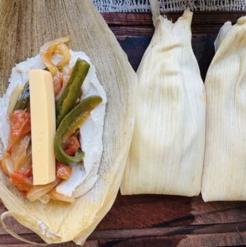 Filling and wrapping vegan tamales on a wooden cutting board